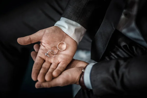 Novio celebración de anillos de boda en la palma, el novio en un traje azul, novio celebración de anillos de boda, los novios de la mano sosteniendo un anillo, anillo de boda en la mano del novio — Foto de Stock