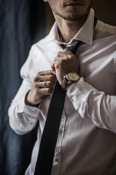 Siyah smokinli ve papyonlu damat beyaz gömlekteki düğmelerini düzeltiyor. Düğün için. Ayrıntılar