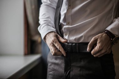 Siyah smokinli ve papyonlu damat beyaz gömlekteki düğmelerini düzeltiyor. Düğün için. Ayrıntılar