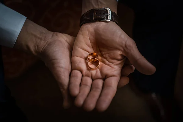 Brudgummen håller vigselringar på handflatan, brudgummen i blå kostym, brudgummen holding vigselringar, katt slickar hand hållande en ring, vigselring i brudgummen hand — Stockfoto