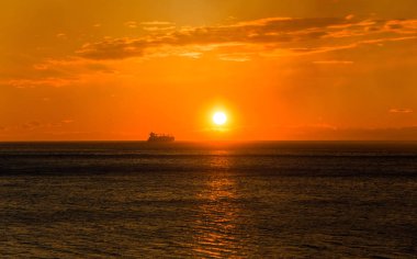 Gün batımında ufukta kargo gemisi