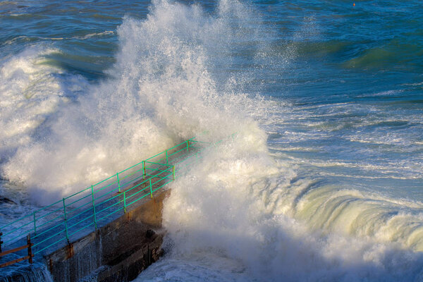Rough Sea Waves Crashing Over a Pier, mediterranean sea, ligurian coast, Italy.