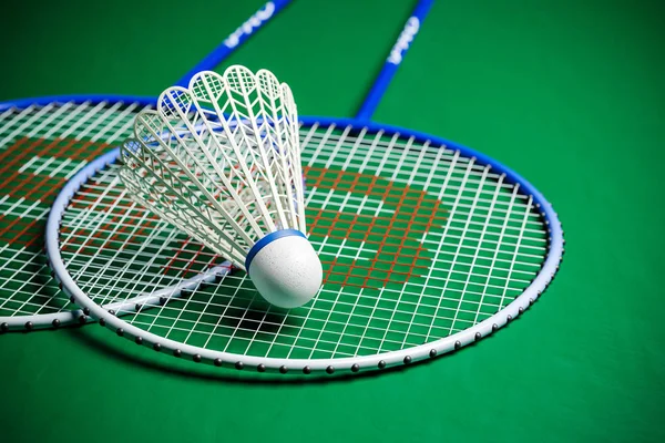 Badminton rackets and shuttlecock on green ground closeup shot. 3D render