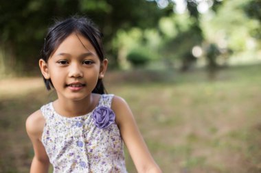 Mor çiçek alan güneş gün arasında duran küçük şirin Asyalı kız. Doğa ile zevk özgürlük.