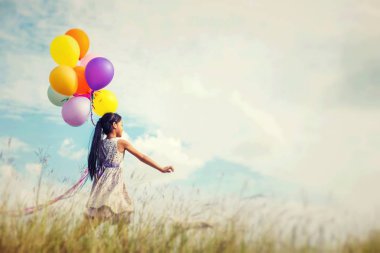 Eller yayılan renkli balonlar çayırda holding mavi gökyüzü ve bulutlar, karşı sevimli küçük kız.