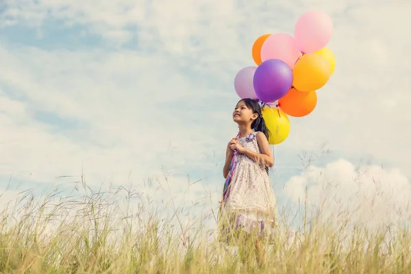 Симпатична Маленька Дівчинка Тримає Барвисті Кульки Лузі Проти Блакитного Неба — стокове фото