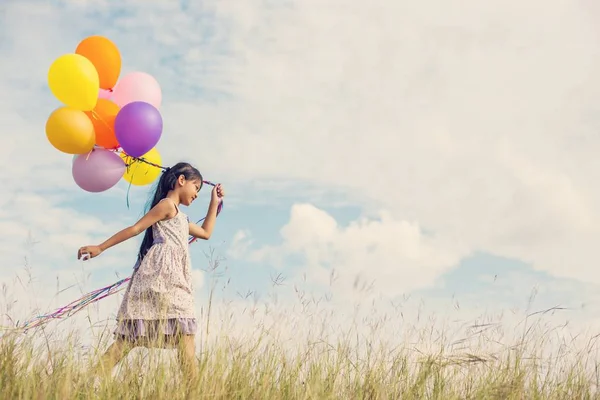 Carina Bambina Che Tiene Palloncini Colorati Nel Prato Contro Cielo — Foto Stock