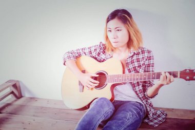 Hipster kadın stil portre zevk ile gitar bakmak çok mutlu.