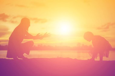 Anne ve küçük kızı günbatımında yürüyüş siluetleri