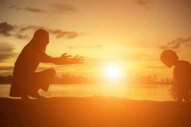 Anne ve küçük kızı günbatımında yürüyüş siluetleri