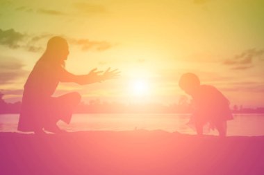 Anne ve küçük kızı günbatımında yürüyüş siluetleri