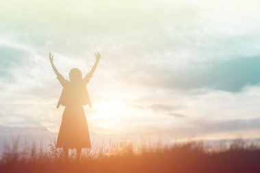 Güzel bir arka plan için dua eden bir kadın silueti.