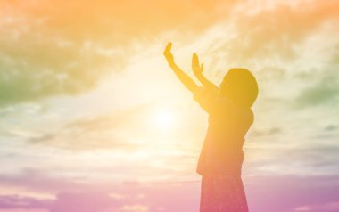 Güzel bir arka plan için dua eden bir kadın silueti.