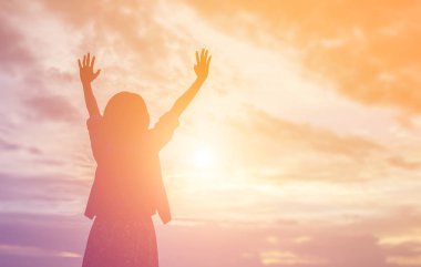 Güzel bir arka plan için dua eden bir kadın silueti.