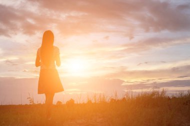 Güzel bir arka plan için dua eden bir kadın silueti.