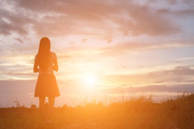 Güzel bir arka plan için dua eden bir kadın silueti.