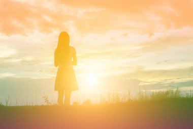 Güzel bir arka plan için dua eden bir kadın silueti.