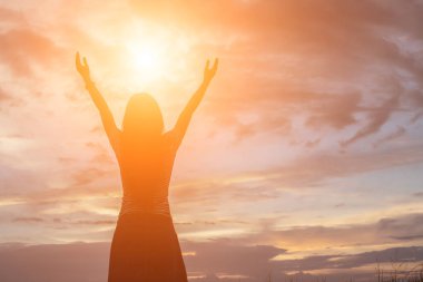 Güzel bir arka plan için dua eden bir kadın silueti.