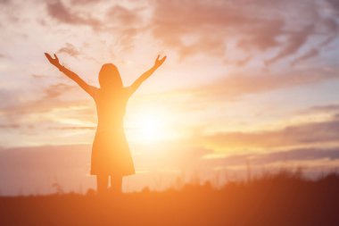 Silhouette of woman praying over beautiful sky background