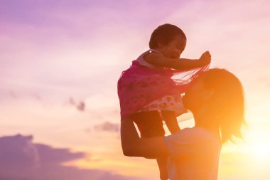 gökyüzü günbatımı bir yaz gününde önünde bir sarılmak için onun sevgi dolu silah siluet bir mutlu genç kız çocuğu anne.