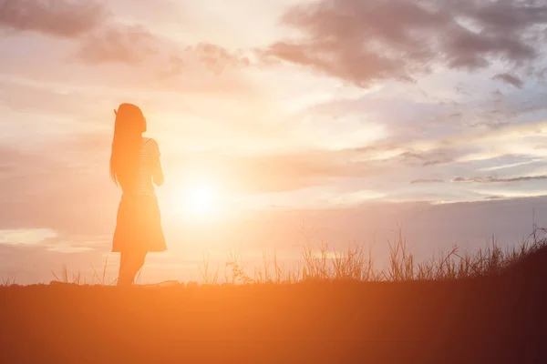 Silhouette of woman praying over beautiful sky background