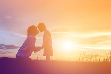 Anne ve küçük kızı günbatımında yürüyüş siluetleri