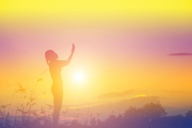 Güzel bir arka plan için dua eden bir kadın silueti.