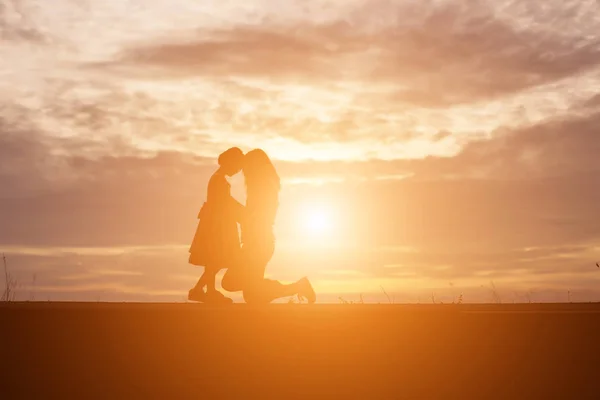 夏の日の空に夕日の前に 抱擁の母は彼の愛情の腕の中幸せな若い女の子子供のシルエット — ストック写真