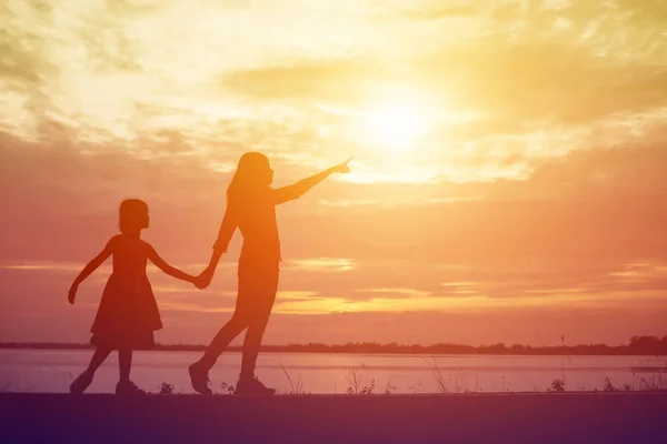 一个快乐的小女孩的剪影 他亲爱的母亲的双臂拥抱 在一个夏日的天空中的日落面前 — 图库照片