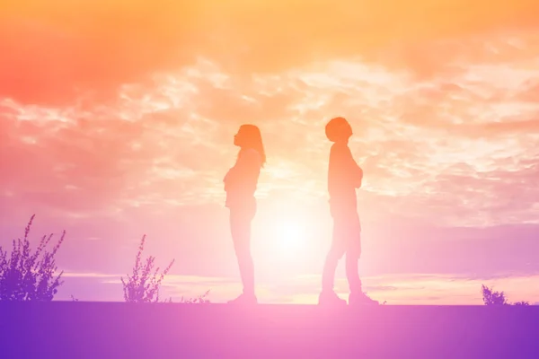 a silhouette of a man and woman holding hands with each other, walking together.