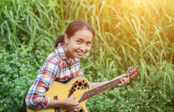 流行に敏感な若い女性が彼の休日にリラックスしてギターを弾くを自然と新鮮な空気をお楽しみください — ストック写真