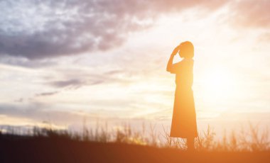 Güzel bir arka plan için dua eden bir kadın silueti.