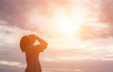 Güzel bir arka plan için dua eden bir kadın silueti.