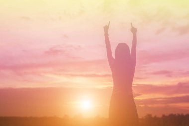 Güzel bir arka plan için dua eden bir kadın silueti.