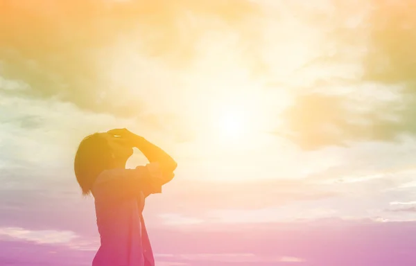 Silhouette of woman praying over beautiful sky background