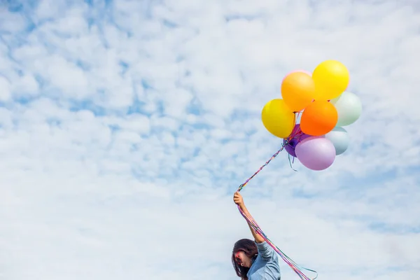 Beautiful Girl jumping with balloons on the beach