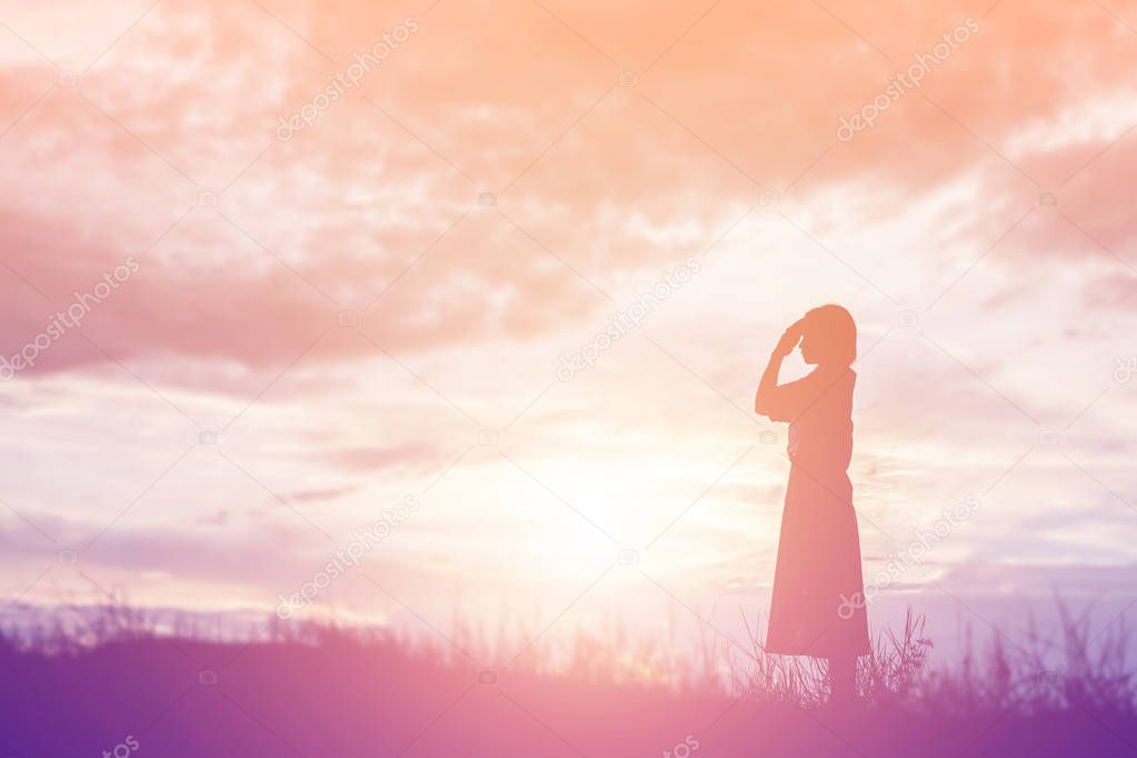 Silhouette of woman praying over beautiful sky background