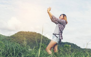 Açık peyzaj, yaşam tarzı dağ doğa arka plan üzerinde genç hippi kadını retro kamera çekimi ile vurdu.