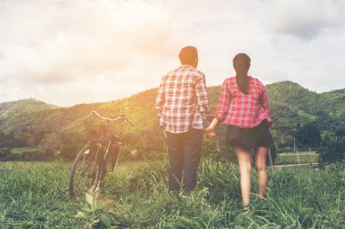 Genç hippi çift elele yürümek çayır rahatlatıcı ve doğal atmosfer çok doğaldır.