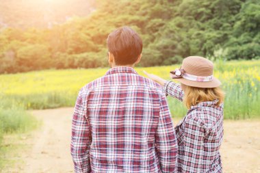 Genç hippi çift sarı çiçek alanında yaz rahatlatıcı. Doğa ile.