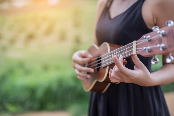 Beautiful woman holding a guitar on his shoulder, Nature park summer outside.