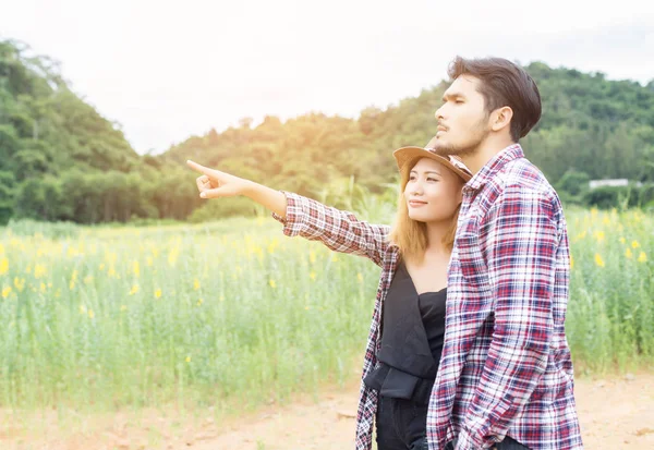 Genç hippi çift sarı çiçek alanında yaz rahatlatıcı. Doğa ile.