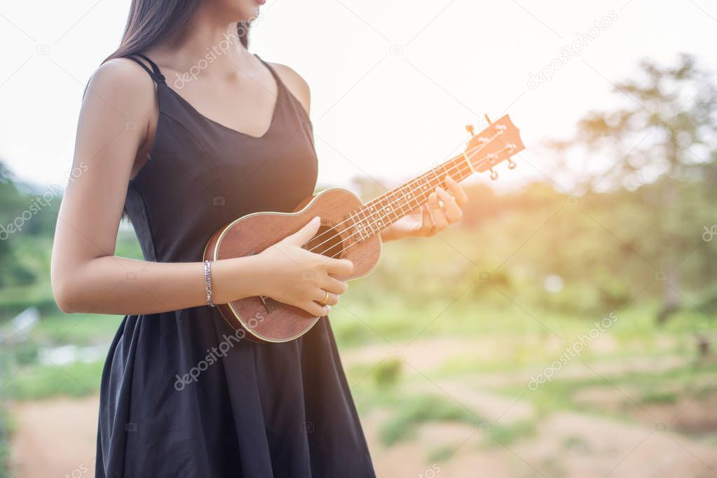 Beautiful woman holding a guitar on his shoulder, Nature park summer outside.