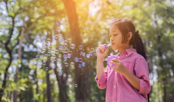 Sevimli küçük kız parkta kabarcıklar üfleme pembe bir gömlek giyiyor, vintage tarzı.
