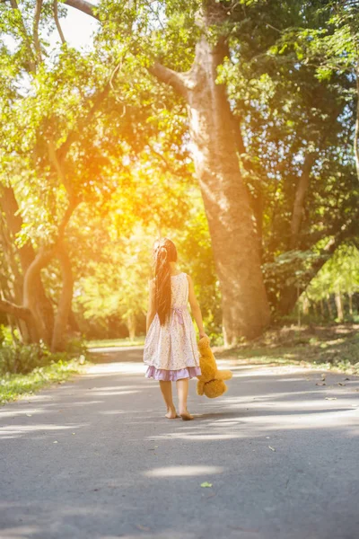 かわいい女の子のスイングに座って テディベア彼女と一緒に座って 女の子は木に指摘した — ストック写真