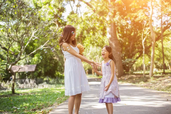 Sevimli küçük kız renkli balonlar tutan, mavi gökyüzü ve bulutlara karşı çayırçalışan.