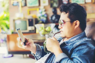 Café'de rahatlatıcı gülümseyen smartphone ile genç adam.