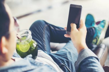 Café'de rahatlatıcı gülümseyen smartphone ile genç adam.