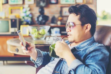 Café'de rahatlatıcı gülümseyen smartphone ile genç adam.