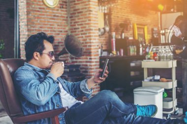 Café'de rahatlatıcı gülümseyen smartphone ile genç adam.